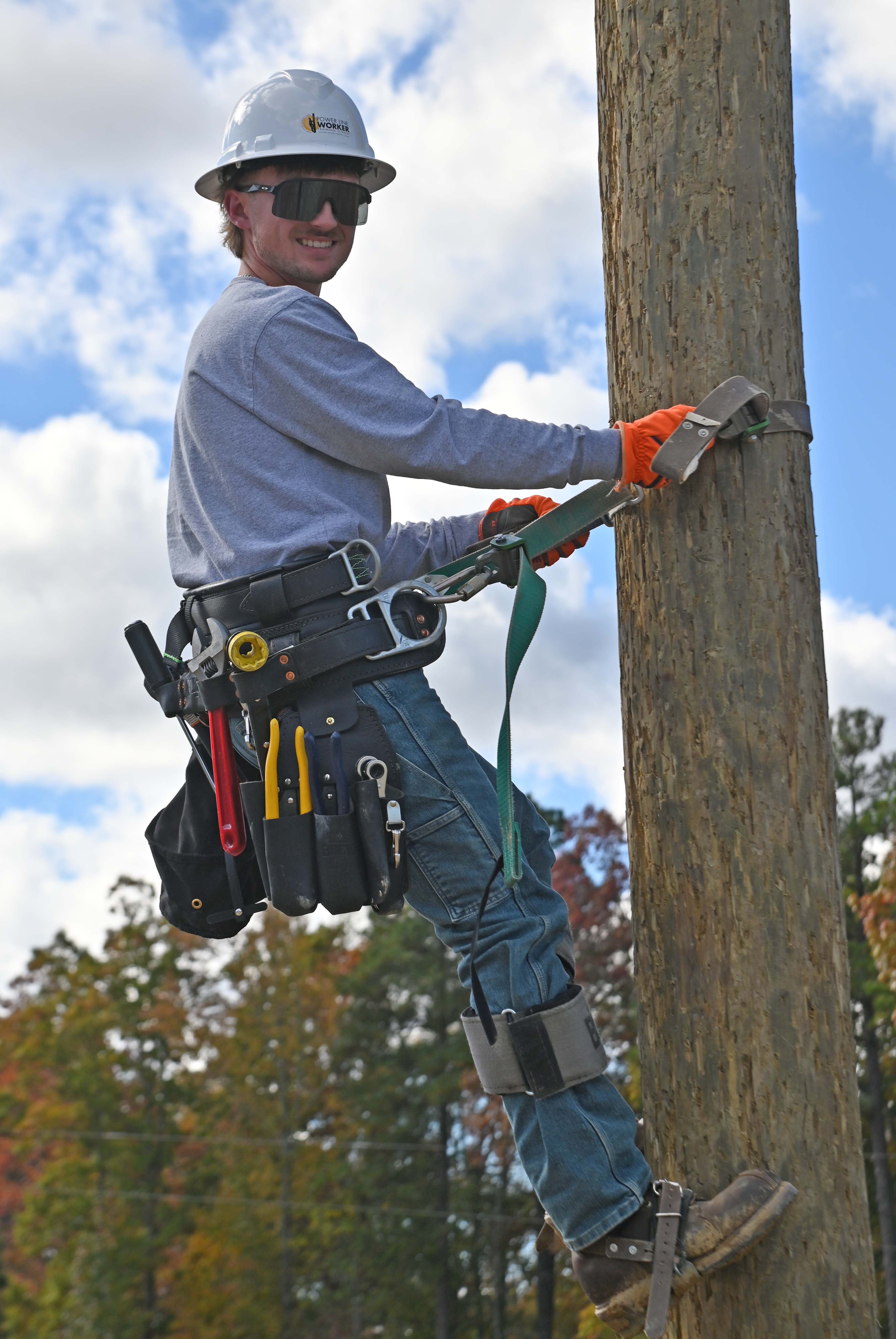 Power Line student Bryce Dennison in PPE climbing a power pole 