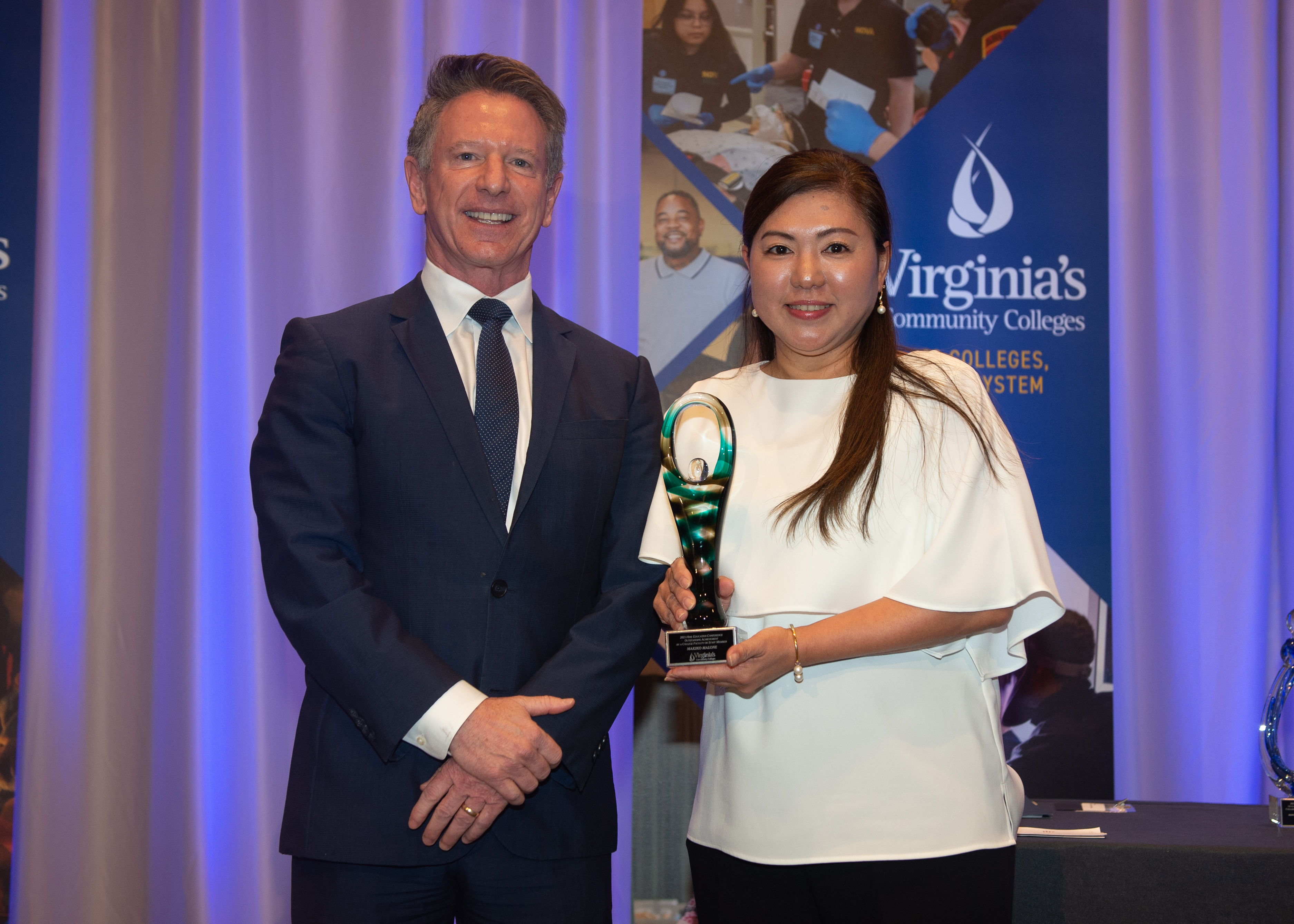 Ms. Malone posing recieving Award from Dr. Dore on stage